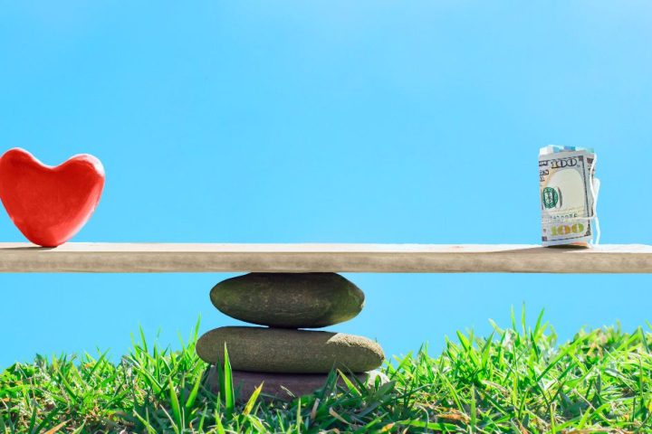 Image of see-saw with a heart on one side and money on the other.